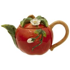 a red ceramic teapot with white flowers and leaves painted on the outside, sitting on a wooden handle