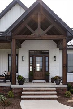 This home has a beautiful front door and porch. The large timber beams look stunning with the white exterior. White Farmhouse Exterior With Cedar Posts, Exterior Mudroom Addition, Post And Beam Front Porch, Front Door Barndominium, White Exterior Barndominium, Wooden Posts Front Porch, White Exterior House With Wood Accents, Wood Pillars Front Porch, Wood Beams Front Porch