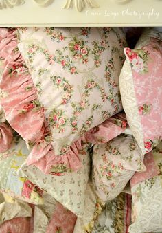 a pile of pillows sitting on top of a white shelf next to a pillow case