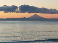 the sun is setting over an ocean with mountains in the distance