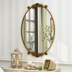 a mirror sitting on top of a dresser next to a table with a basket and candle