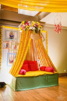 a bed covered in yellow and red flowers on top of a hard wood floor next to a wall