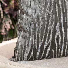 a zebra print pillow sitting on top of a white chair next to flowers and plants