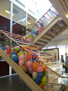 an escalator with balloons and streamers on it in the lobby at a school