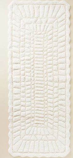 a white blanket with ruffled edges hanging on a wall next to a wooden floor