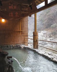 an indoor hot tub with water running down the side and bamboo walls on either side