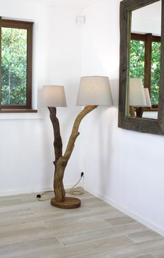 a lamp that is next to a tree in a room with two mirrors on the wall