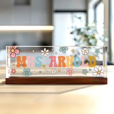 a clear acrylic sign with flowers and the word mrs arnold on it