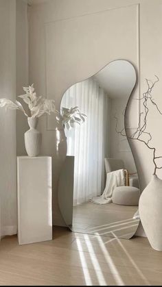 a large white vase sitting on top of a hard wood floor next to a mirror