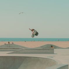 a man flying through the air while riding a skateboard on top of cement ramps