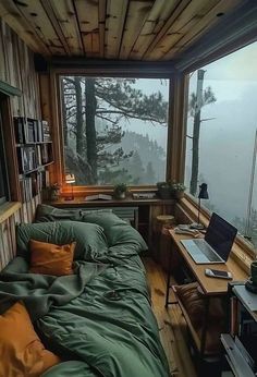 a bed sitting under a window next to a desk with a laptop on top of it