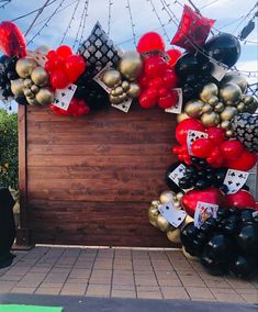 a bunch of balloons that are on the side of a wall in front of a fence