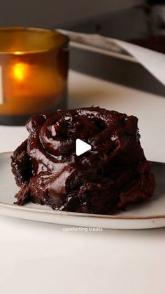 a white plate topped with chocolate cake next to a candle