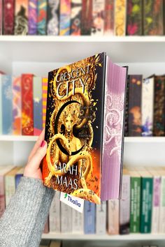 a person holding up a book in front of a bookshelf full of books