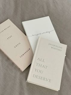 two books sitting on top of a bed next to each other with writing on them