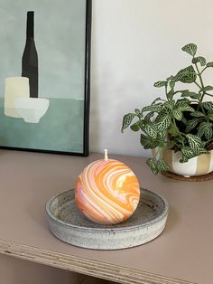 a candle sitting on top of a plate next to a potted plant