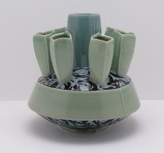 a green vase sitting on top of a white table