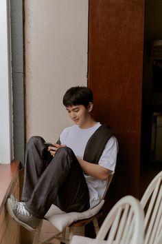 a young man sitting in a chair looking at his cell phone