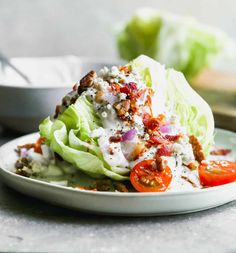 lettuce and tomato salad on a white plate with dressing in the middle, ready to be eaten