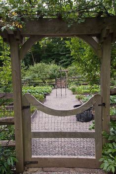 an open wooden gate in the middle of a garden