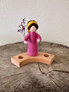 a small doll is standing on a piece of wood