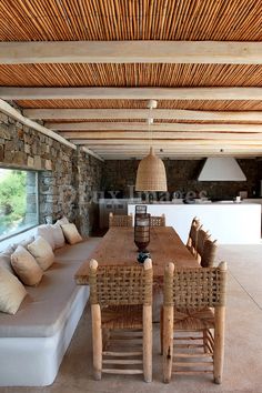 an outdoor living area with couches, tables and lamps on the ceiling in front of a stone wall