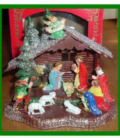 a nativity scene with figurines in front of a red box on a table