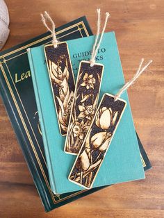 two bookmarks sitting on top of a wooden table next to a ball of yarn