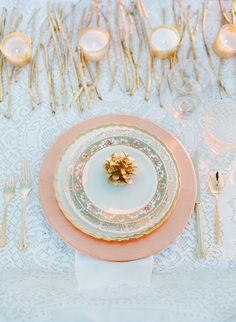 a table set with plates, silverware and gold cutlery is shown in this image