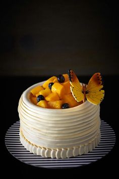 there is a cake with fruit in the middle and a butterfly sitting on top of it