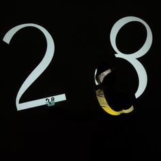 a man standing in front of the numbers on a black wall with his head tilted to the side