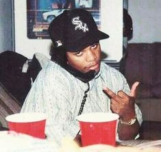 a man sitting at a table with two cups in front of him and pointing to the side