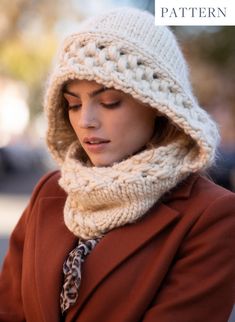 a woman wearing a hat and scarf while looking at her cell phone