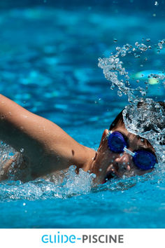 a young boy swimming in a pool with goggles on his head and water splashing around him