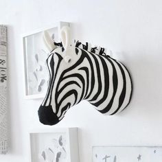 a zebra head mounted to the side of a white wall next to pictures and framed photographs