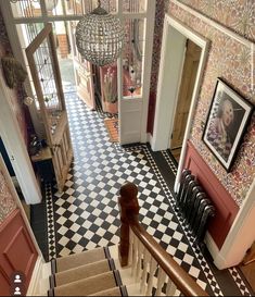 an aerial view of a hallway with stairs and pictures on the wall, in front of a doorway