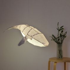 an origami lamp hanging from the ceiling next to a plant