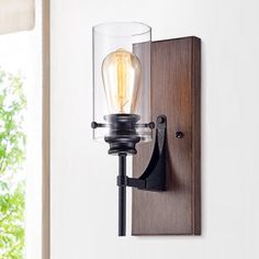 a light fixture mounted on a wall with a glass shade and wood frame around it