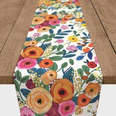 the table runner is decorated with colorful flowers and leaves on white paper, along with brown wood planks