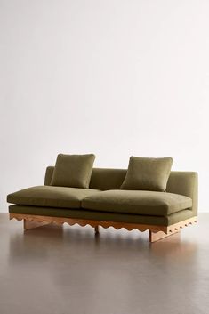 a green couch sitting on top of a hard wood floor next to a white wall