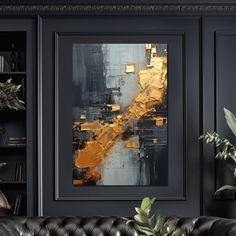 a living room with black leather couches and gold foil artwork on the wall above it