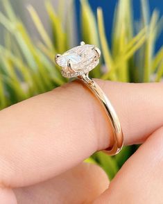 a close up of a person's hand holding a ring with a diamond on it