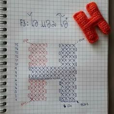 a piece of crochet next to a knitted letter h on a notebook