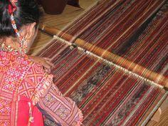 a woman is weaving fabric on a loom with her hands and looking at it