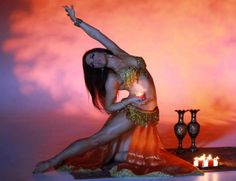 a woman in a belly dance pose next to candles