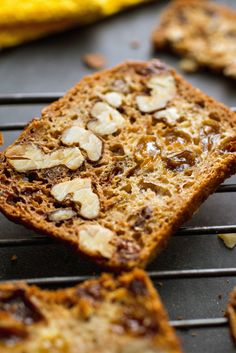 slices of bread with nuts sitting on top of a cooling rack next to a banana