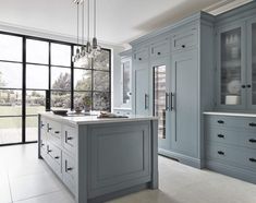 a large kitchen with blue cabinets and marble counter tops, along with an island in the middle