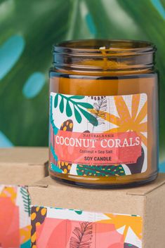 a jar of coconut and corals soy candle sitting on top of a cardboard box