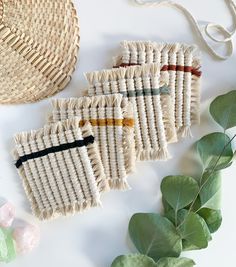 three pieces of woven fabric sitting on top of a table next to some green leaves