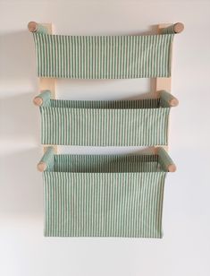 two green and white striped bedspreads hanging on a wall with wooden pegs